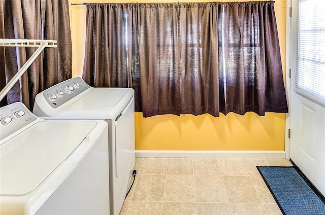 laundry room featuring light tile patterned floors, washing machine and dryer, and a wealth of natural light