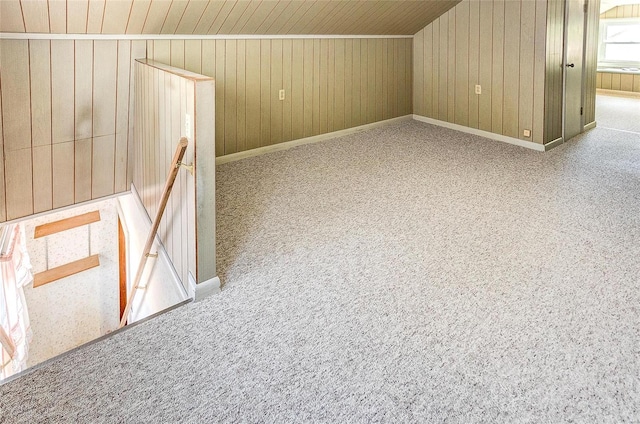 additional living space featuring carpet flooring and wood walls