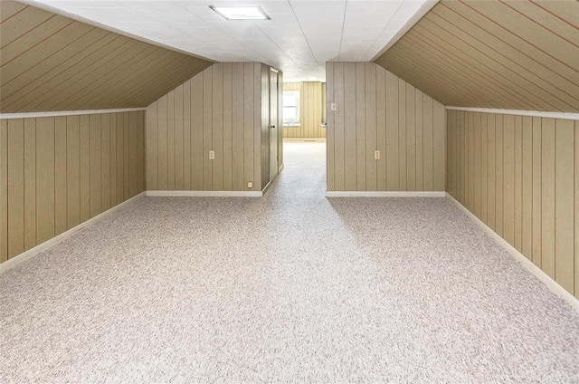 additional living space featuring carpet, lofted ceiling, and wooden walls