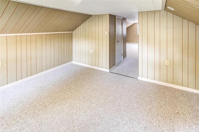 bonus room featuring carpet flooring, wood walls, and vaulted ceiling