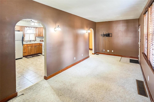 unfurnished room featuring light colored carpet, ceiling fan, and sink