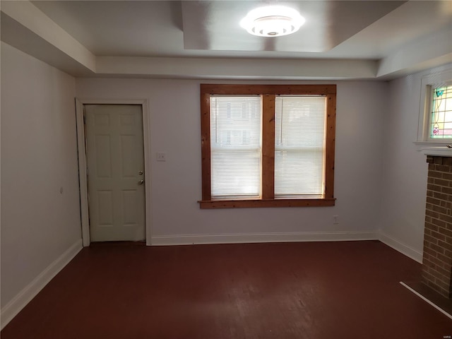 empty room featuring a tray ceiling and dark hardwood / wood-style flooring