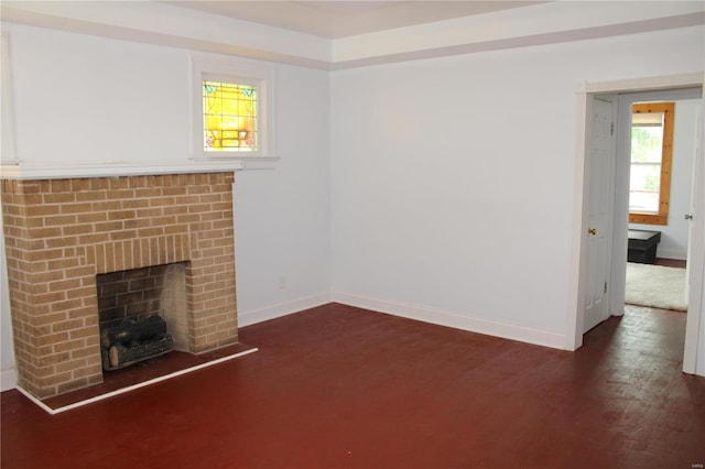 unfurnished living room featuring a wealth of natural light, dark wood-type flooring, and a brick fireplace