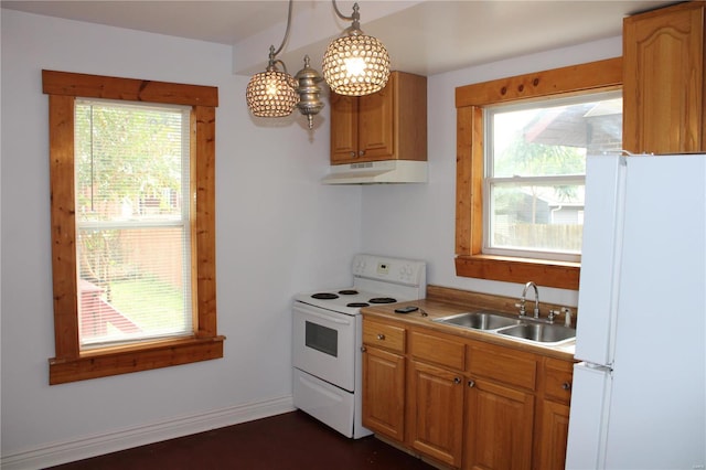 kitchen with hanging light fixtures, sink, white appliances, and a healthy amount of sunlight