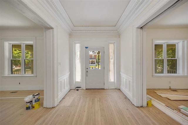 entryway with light hardwood / wood-style flooring, ornamental molding, and a healthy amount of sunlight