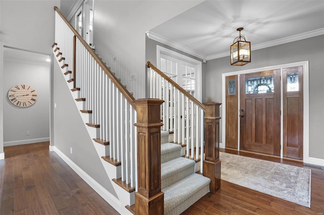 entryway with ornamental molding, dark wood-type flooring, and a chandelier