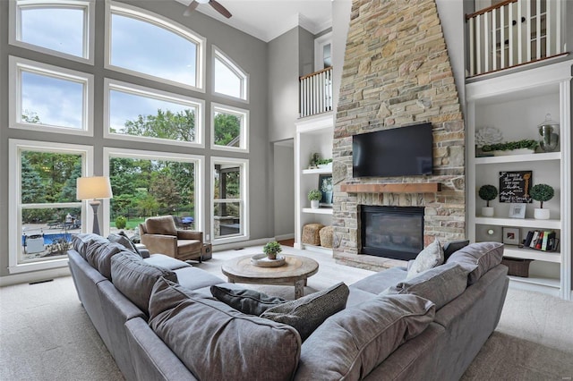 carpeted living room with a fireplace, built in features, and a towering ceiling