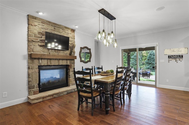 dining room featuring a stone fireplace, crown molding, and dark hardwood / wood-style flooring