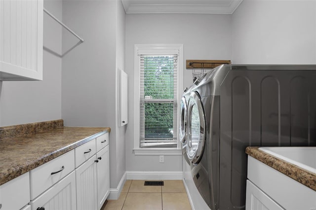 washroom with washer and dryer, light tile patterned floors, cabinets, and crown molding