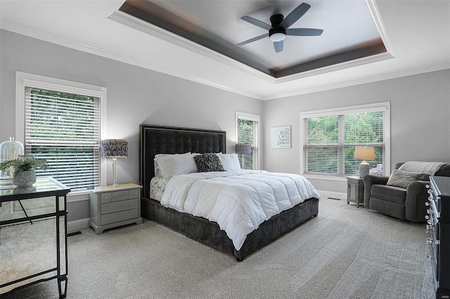 bedroom with multiple windows, light carpet, a raised ceiling, and ceiling fan