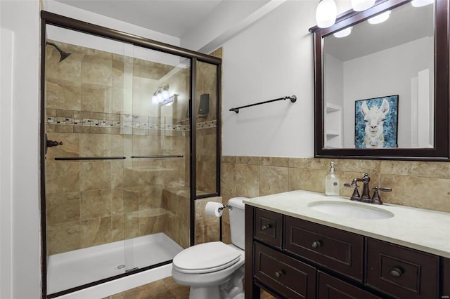 bathroom with vanity, toilet, tile walls, and walk in shower