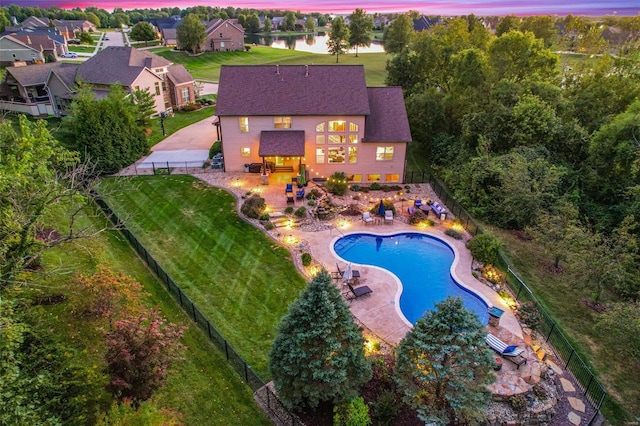 pool at dusk with a patio and a water view