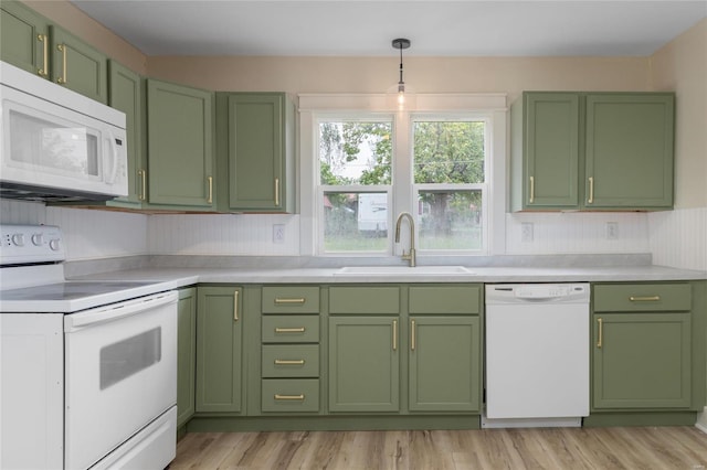 kitchen featuring light wood-type flooring, sink, decorative light fixtures, green cabinetry, and white appliances