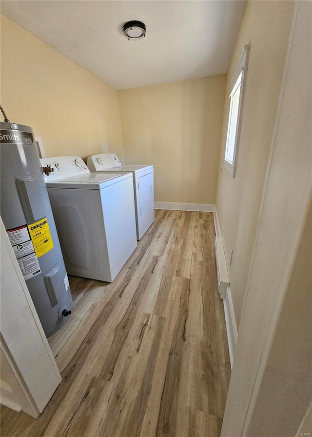 clothes washing area with light hardwood / wood-style floors, water heater, and separate washer and dryer