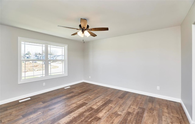 unfurnished room with dark wood-style floors, a ceiling fan, visible vents, and baseboards