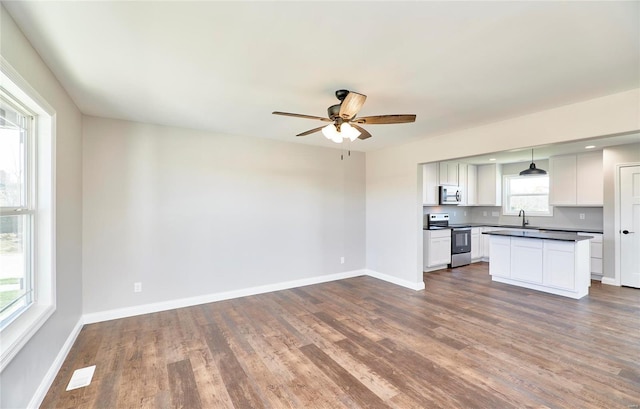 kitchen featuring stainless steel appliances, dark countertops, dark wood finished floors, and baseboards