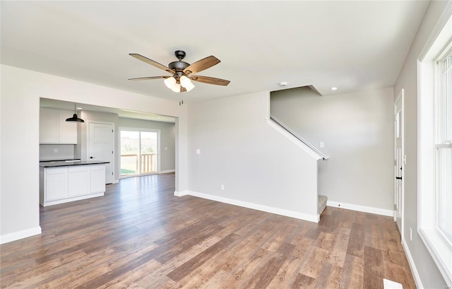 unfurnished living room featuring ceiling fan, recessed lighting, wood finished floors, baseboards, and stairs