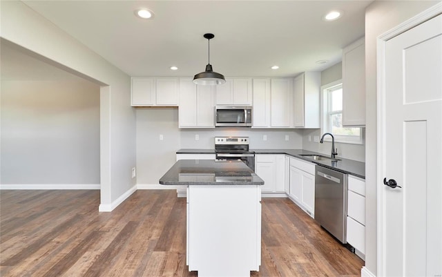 kitchen with a kitchen island, a sink, white cabinetry, appliances with stainless steel finishes, and dark wood-style floors