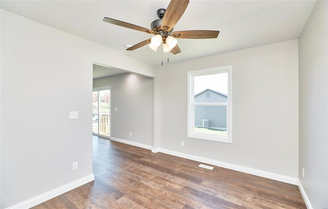 spare room featuring a ceiling fan, visible vents, baseboards, and wood finished floors