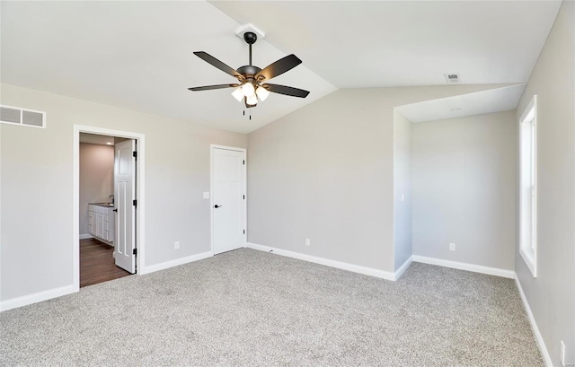 unfurnished bedroom featuring baseboards, visible vents, ensuite bathroom, vaulted ceiling, and carpet floors