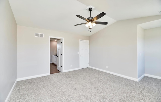 carpeted empty room with lofted ceiling, ceiling fan, visible vents, and baseboards