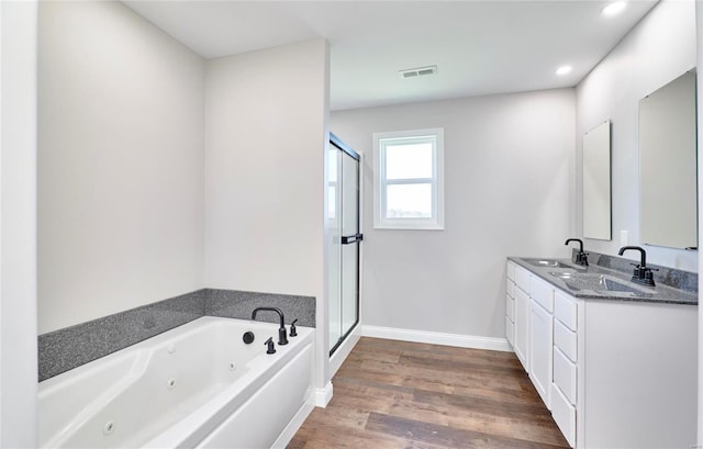 bathroom featuring a stall shower, visible vents, wood finished floors, a whirlpool tub, and a sink