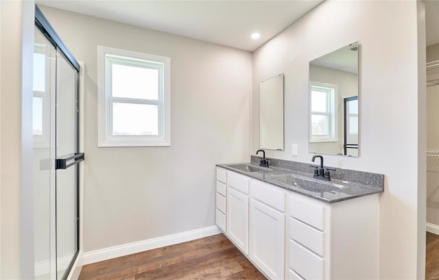 bathroom featuring double vanity, wood finished floors, a sink, and baseboards