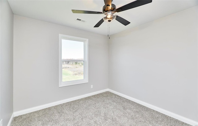 spare room with carpet floors, a ceiling fan, visible vents, and baseboards