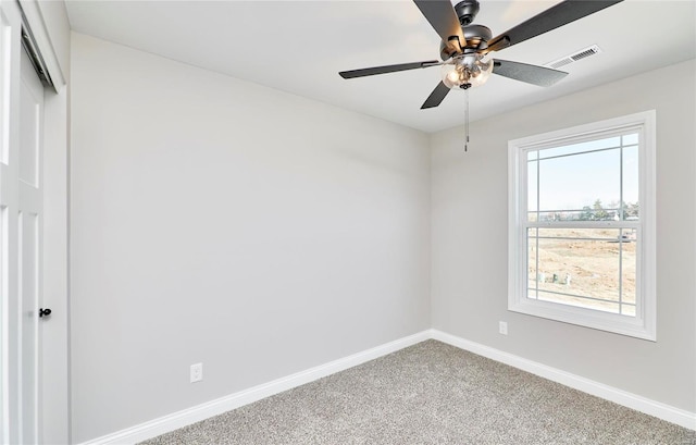 carpeted spare room featuring ceiling fan, visible vents, and baseboards