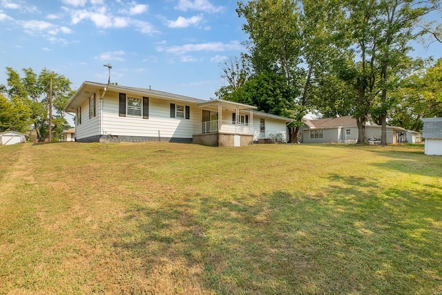 back of house with a storage shed and a yard