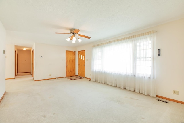 carpeted spare room with a textured ceiling and ceiling fan