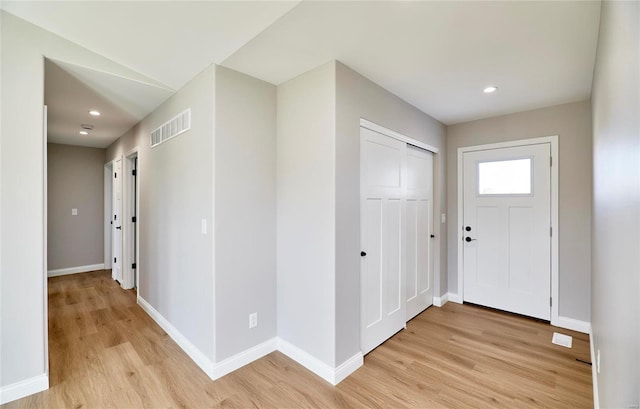 foyer featuring light wood-style floors, visible vents, and baseboards