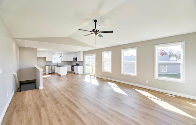 unfurnished living room featuring vaulted ceiling, sink, ceiling fan, and light hardwood / wood-style floors