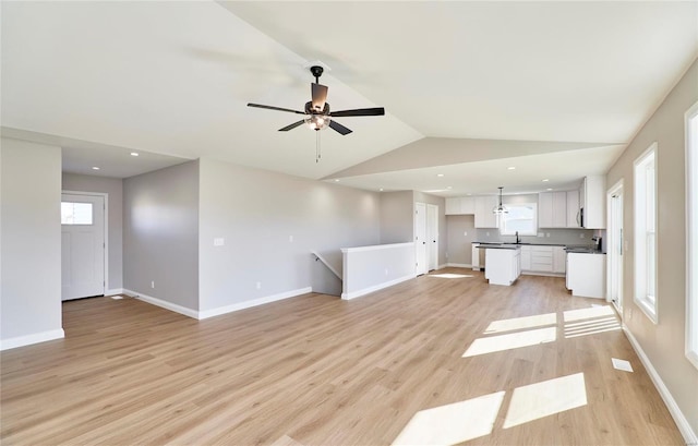 unfurnished living room with ceiling fan, light hardwood / wood-style floors, lofted ceiling, and sink