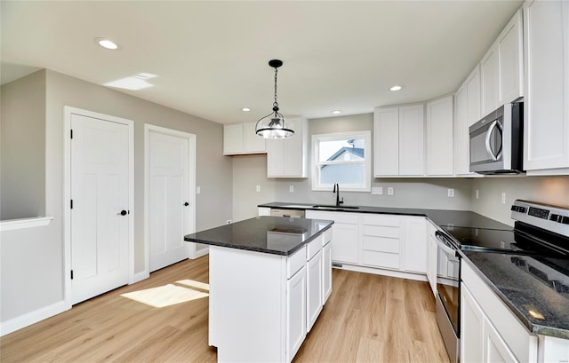 kitchen with white cabinets, sink, light wood-type flooring, a kitchen island, and stainless steel appliances