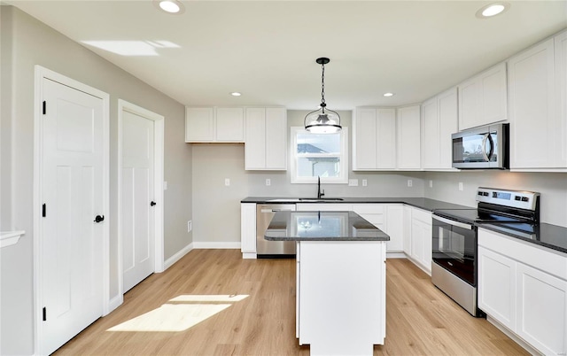 kitchen with a center island, light hardwood / wood-style flooring, appliances with stainless steel finishes, decorative light fixtures, and white cabinetry