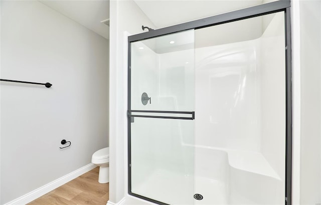 bathroom with hardwood / wood-style floors, toilet, and an enclosed shower