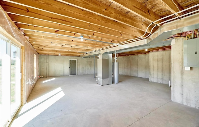 basement with electric panel, heating unit, and water heater