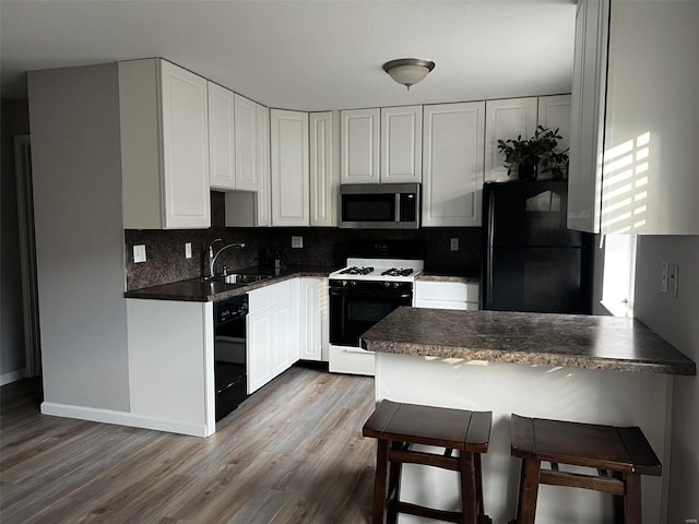 kitchen featuring black appliances, a kitchen breakfast bar, white cabinets, sink, and light hardwood / wood-style flooring