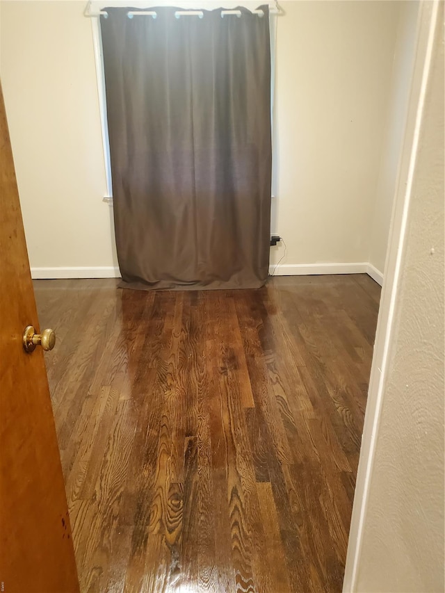 spare room featuring baseboards and wood finished floors