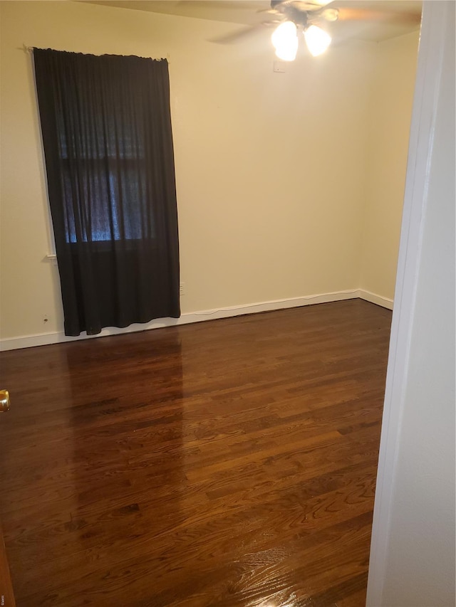 unfurnished room with baseboards, ceiling fan, and dark wood-style floors