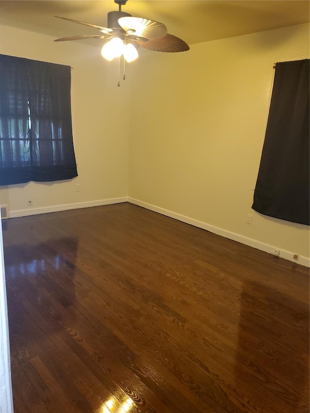 spare room featuring baseboards, a ceiling fan, and dark wood-style floors