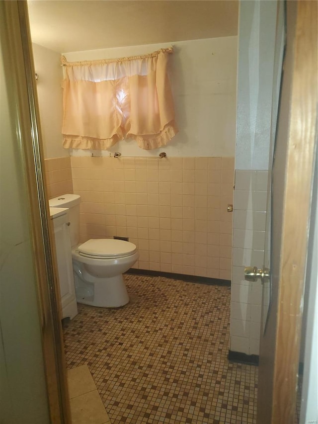 bathroom featuring toilet, tile walls, and a wainscoted wall