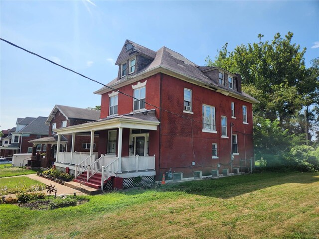 view of side of home with a lawn and covered porch