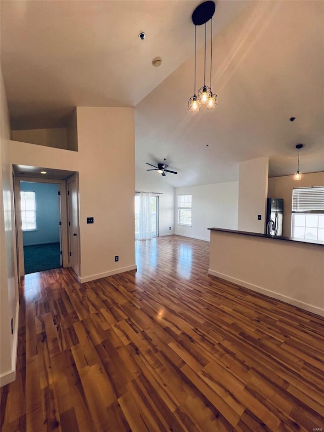 unfurnished living room with dark wood-type flooring, plenty of natural light, and ceiling fan