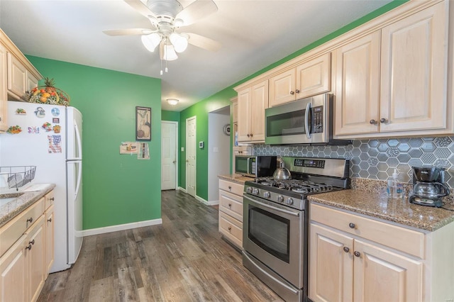 kitchen with light stone counters, dark hardwood / wood-style floors, stainless steel appliances, backsplash, and ceiling fan