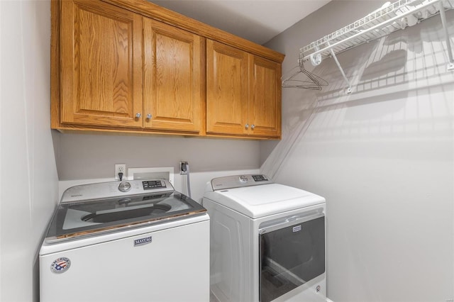 clothes washing area featuring washer and clothes dryer and cabinets