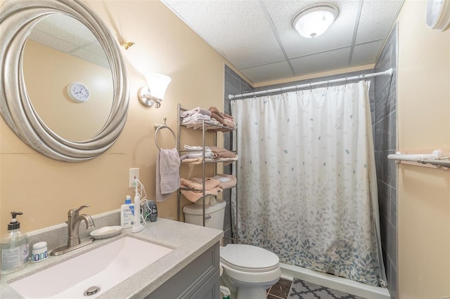 bathroom featuring a shower with curtain, vanity, a drop ceiling, toilet, and tile patterned floors