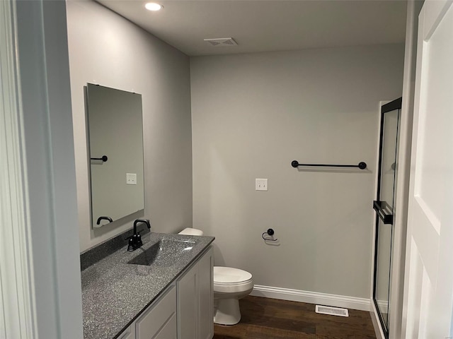 bathroom featuring vanity, hardwood / wood-style floors, walk in shower, and toilet