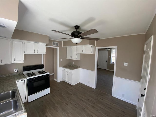 kitchen with gas range gas stove, sink, white cabinets, dark hardwood / wood-style flooring, and ceiling fan